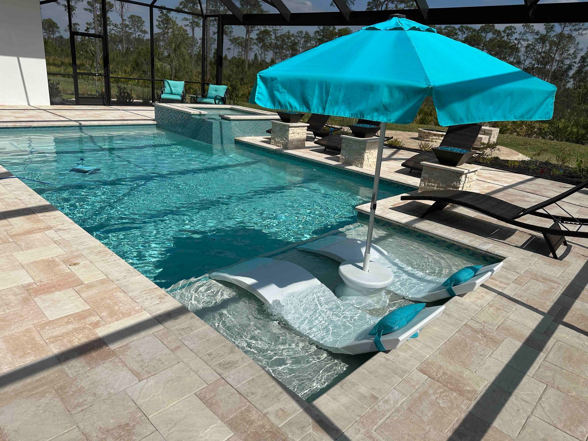 A luxurious swimming pool with lounge chairs in the water and a teal umbrella for shade.