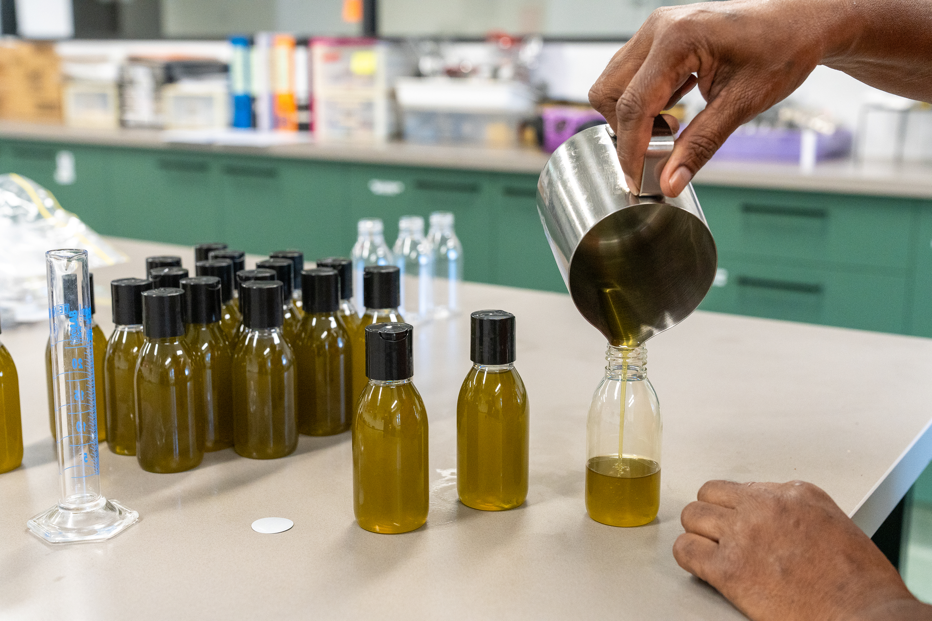 A person is pouring liquid into a bottle in a laboratory.