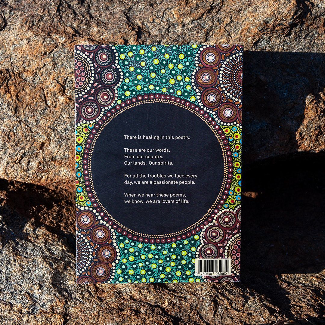 A book titled arelhkenha angkentyn women 's talk is sitting on a rock.