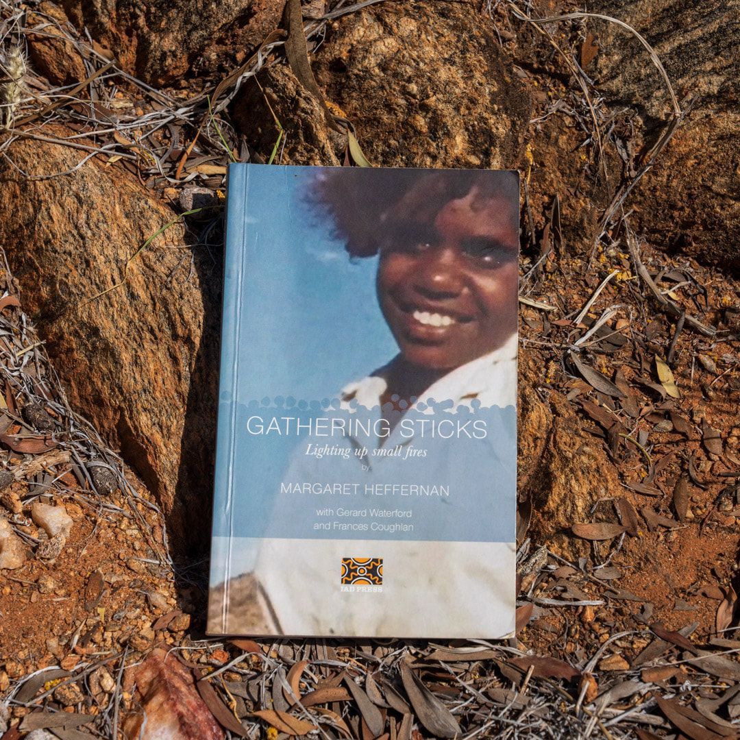 A book titled gathering sticks is sitting on the ground