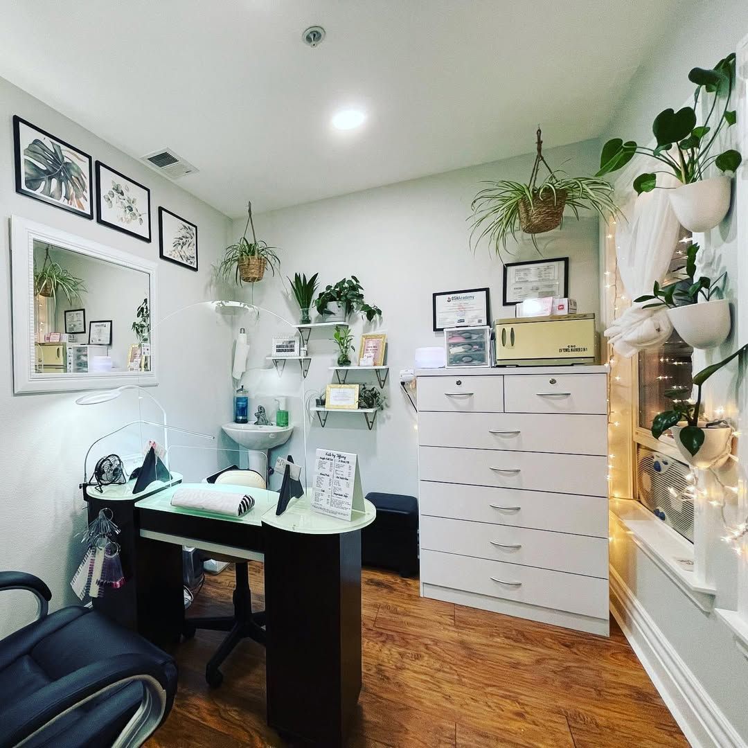 Bright, plant-filled home office with desk, white drawers, mirror, and warm wood floor.