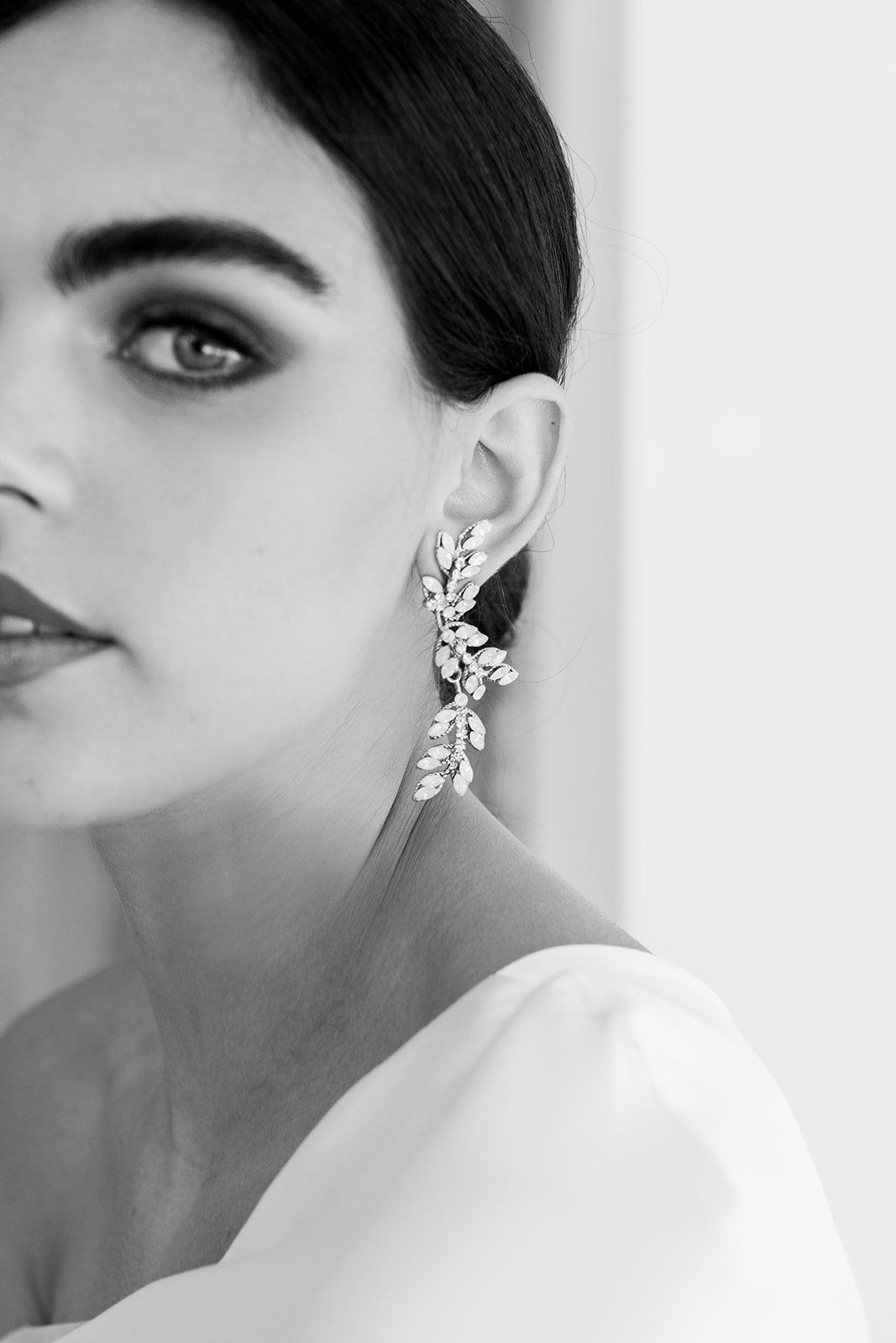 A black and white photo of a woman wearing earrings.