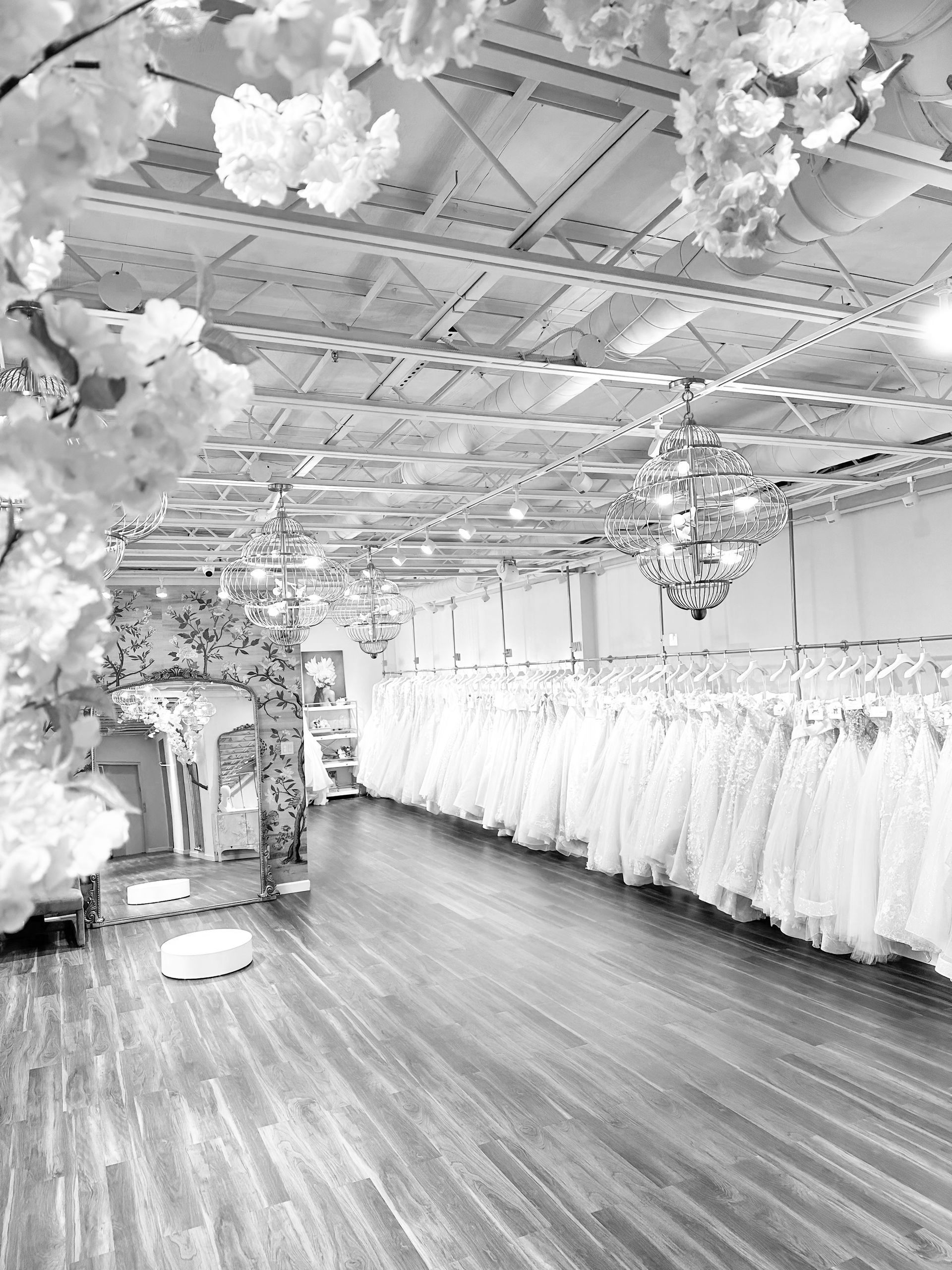 A black and white photo of a wedding dress store filled with lots of wedding dresses.
