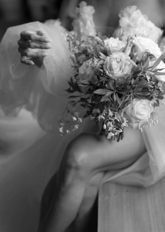 A black and white photo of a bride holding a bouquet of flowers.