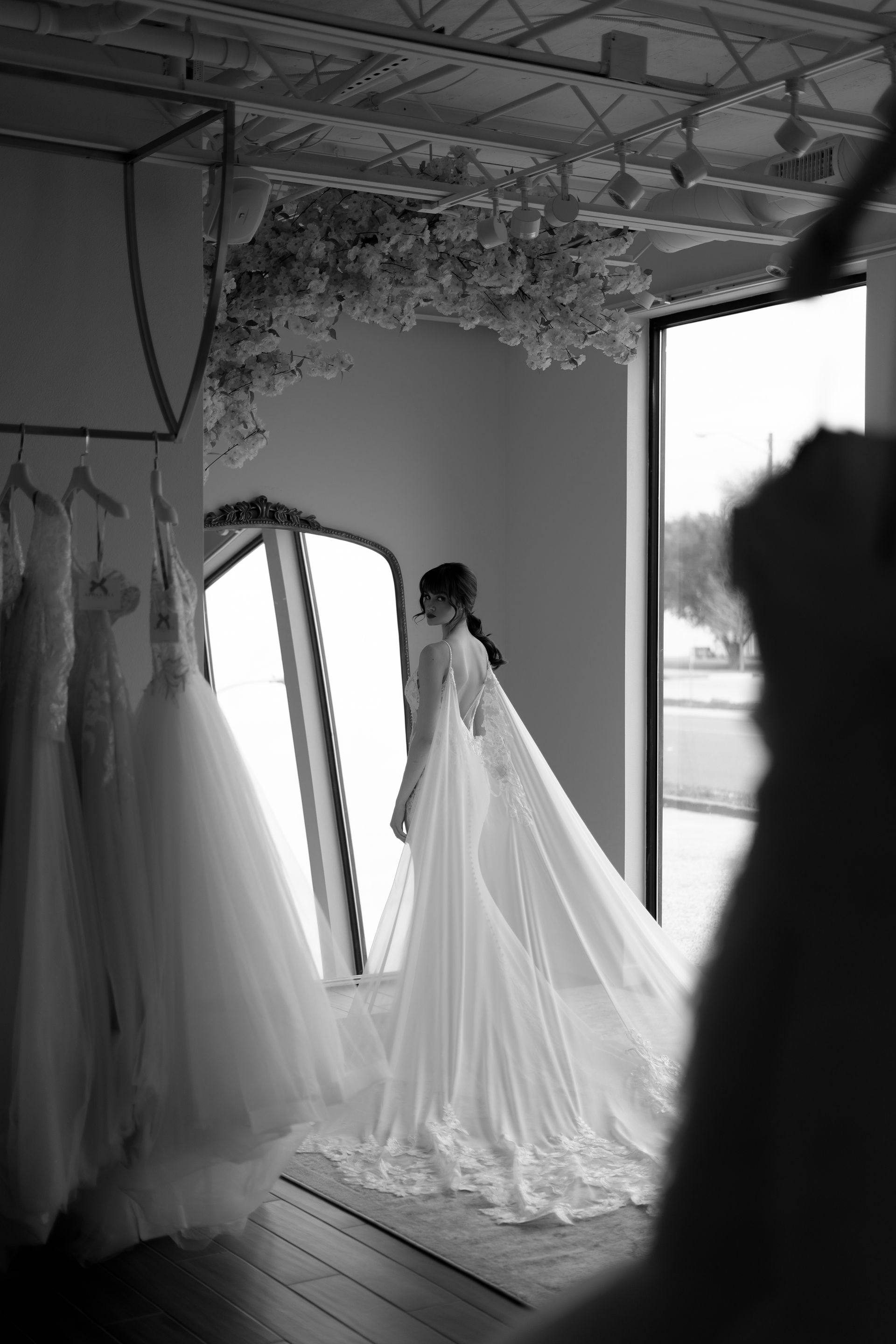 A woman in a wedding dress is standing in front of a mirror in a room.