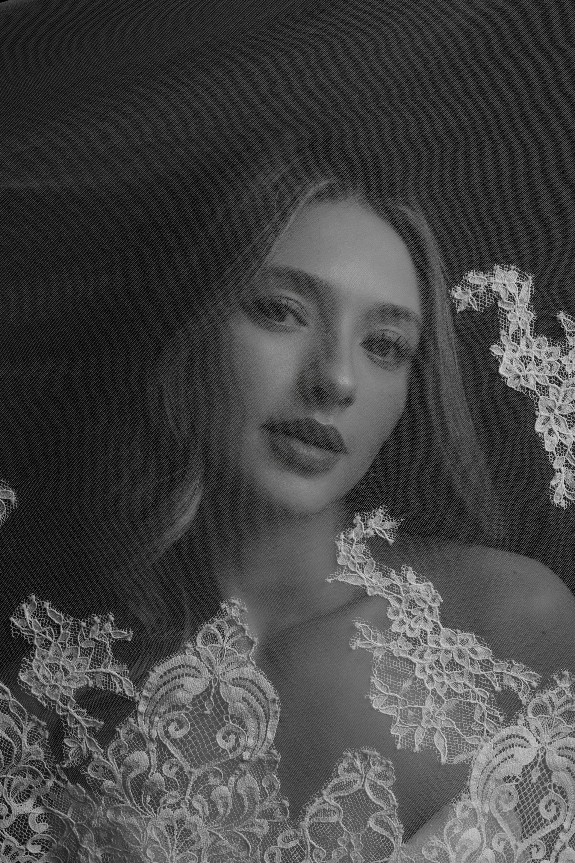 A woman in a wedding dress is standing in front of a window.
