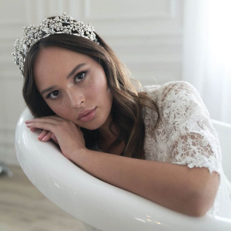 A woman wearing a tiara is sitting in a bathtub