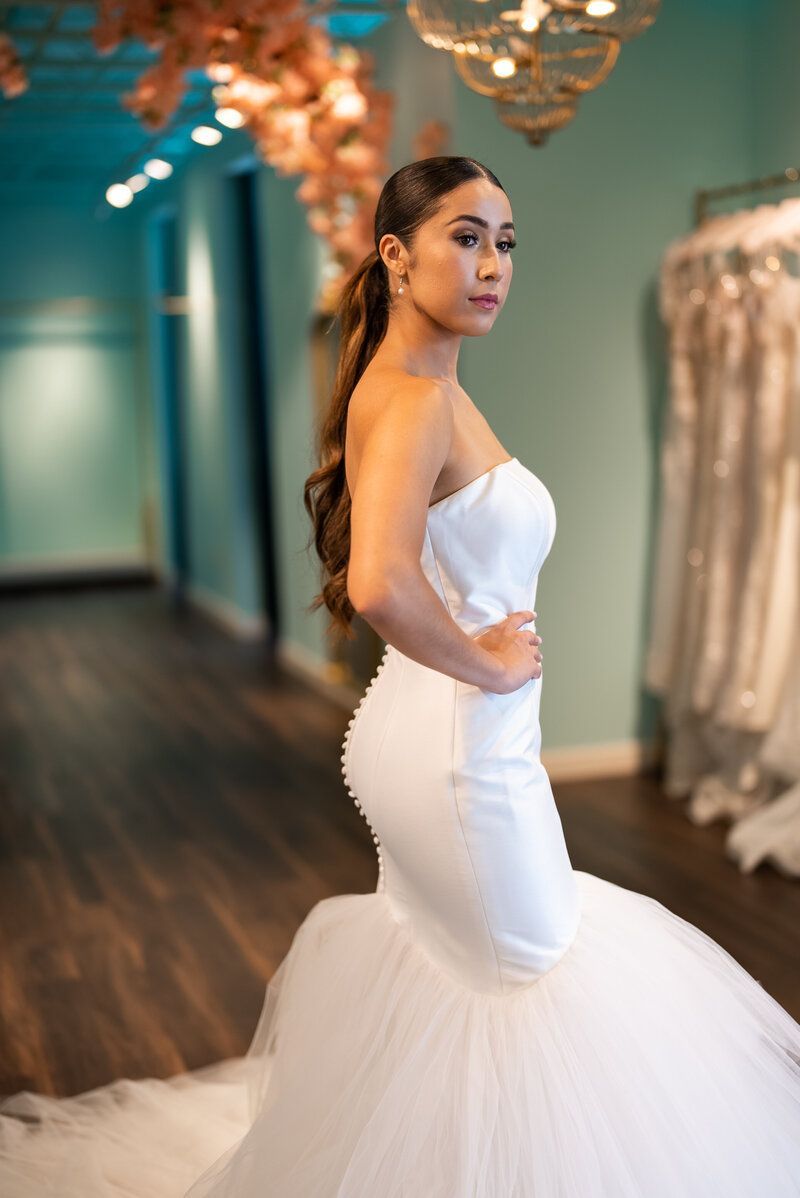 A woman in a white wedding dress is standing in a hallway.