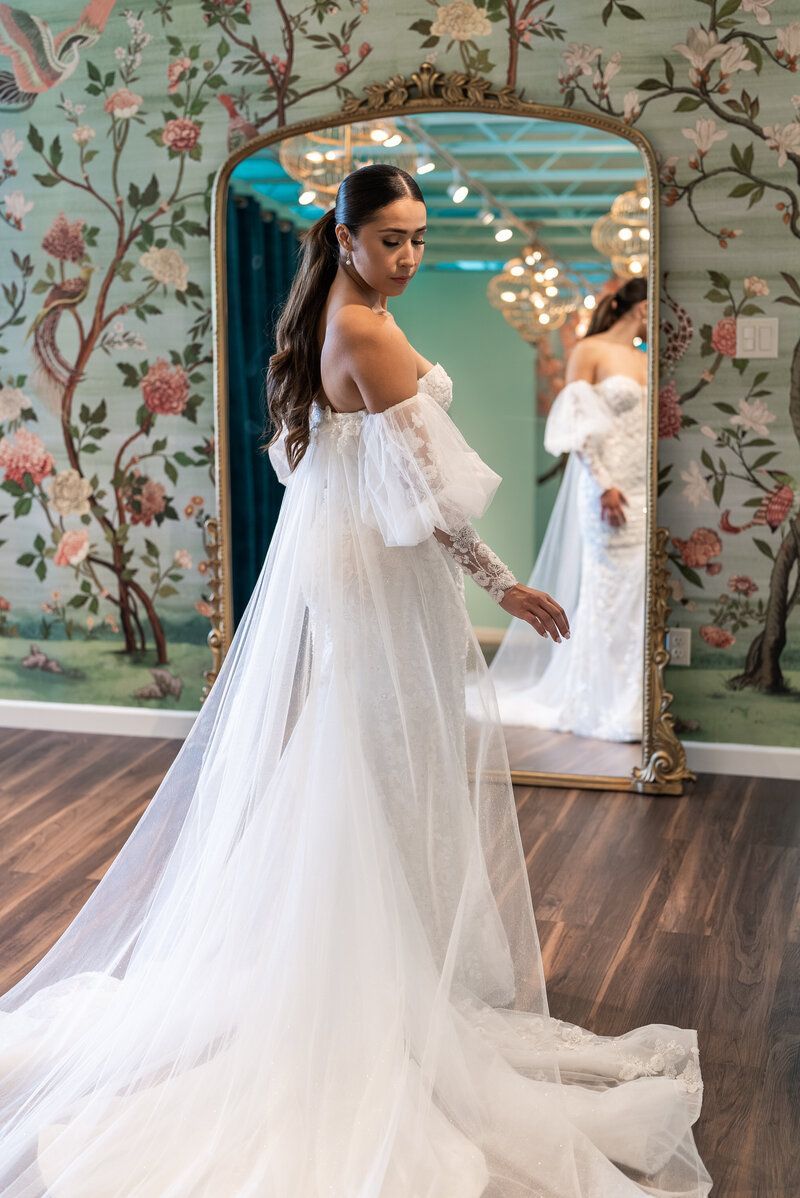 A woman in a wedding dress is standing in front of a mirror.