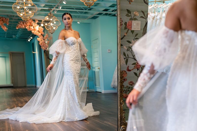 A woman is trying on a wedding dress in front of a mirror.