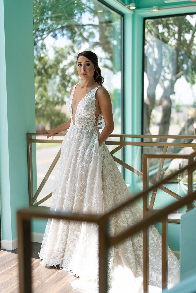 A woman in a wedding dress is standing in front of a window.
