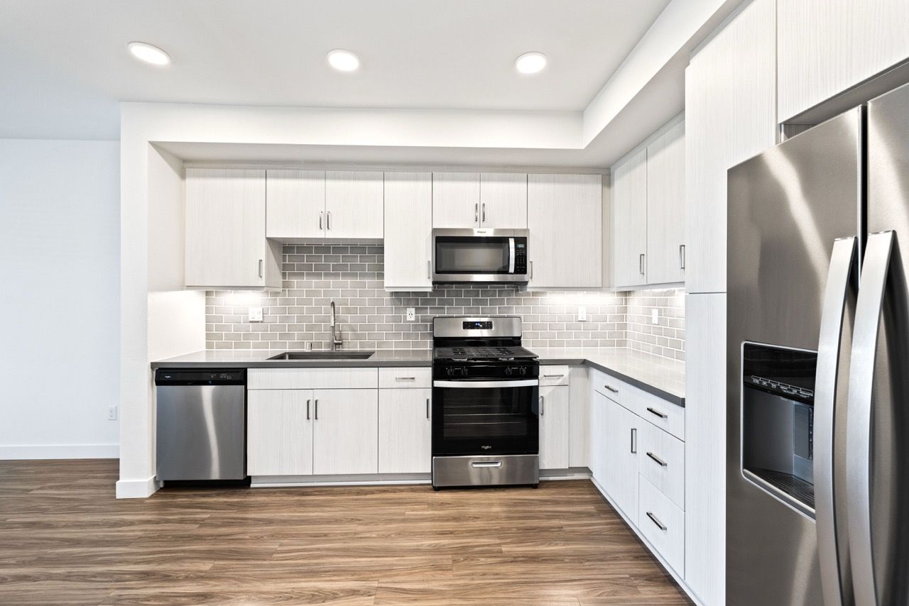 Modern kitchen with white cabinets, stainless steel appliances, and gray subway tile backsplash.