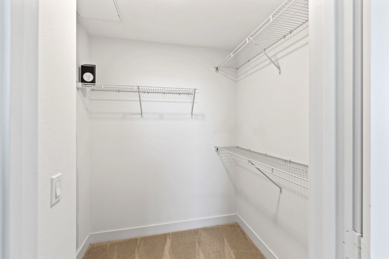 White walk-in closet with wire shelves and a small safe on the top shelf.