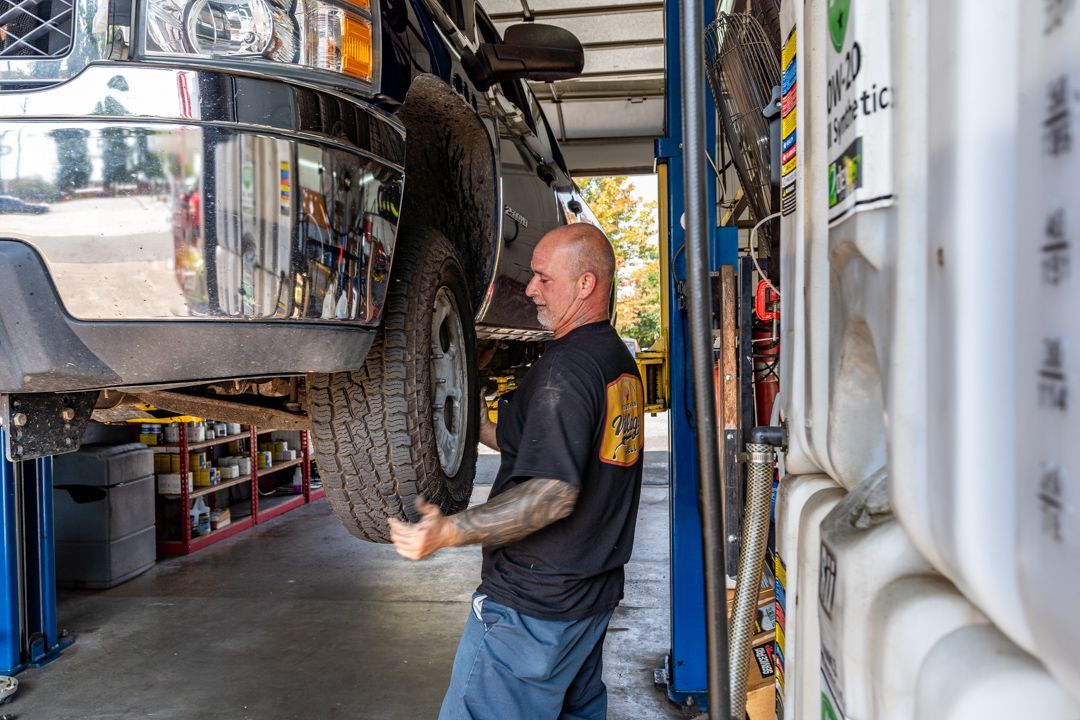Mechanic lifting a tire of a truck inside a garage.