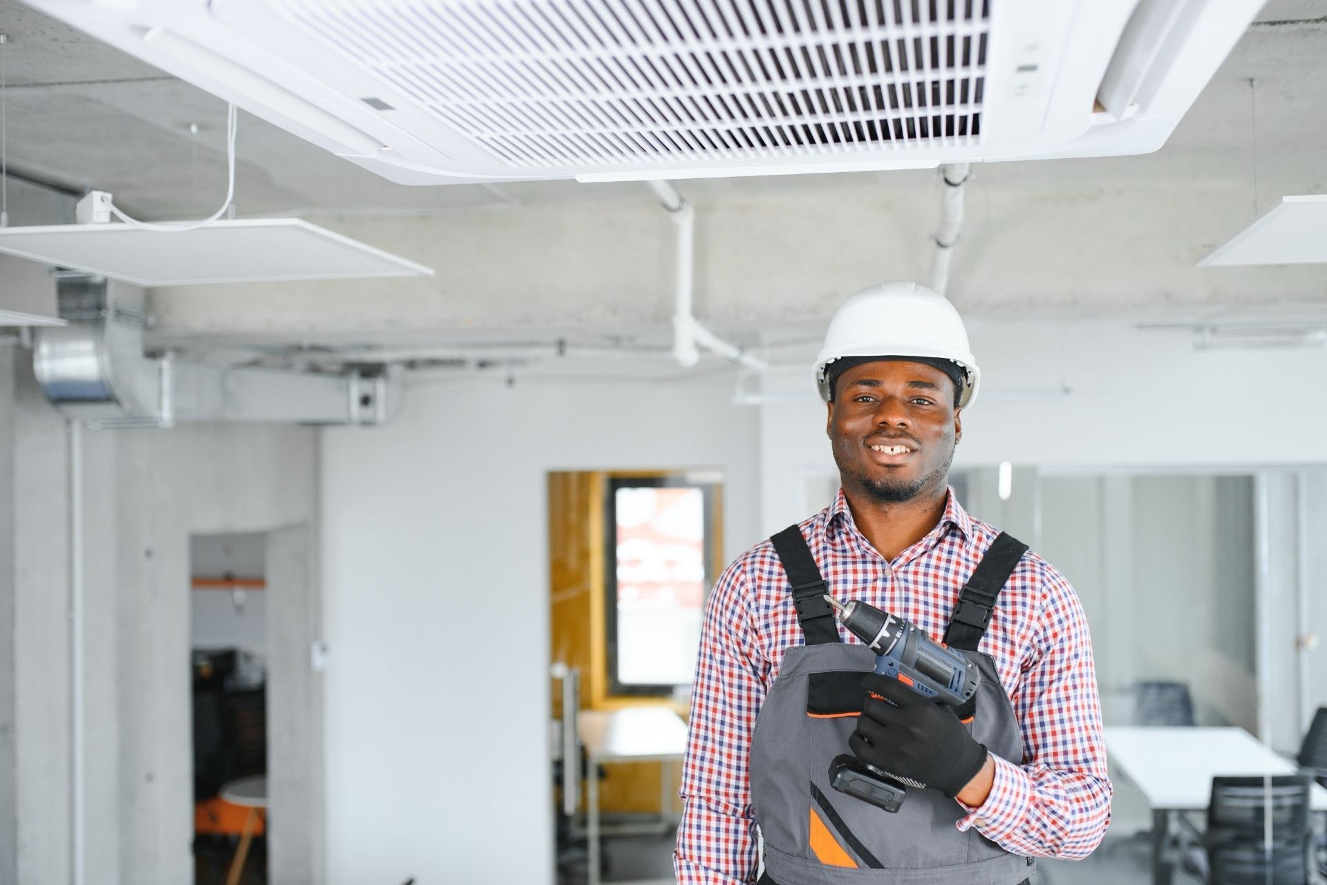 HVAC technician wearing mask and hard hat, working on AC units on a rooftop. HVAC technician wearing mask and hard hat, working on AC units on a rooftop.