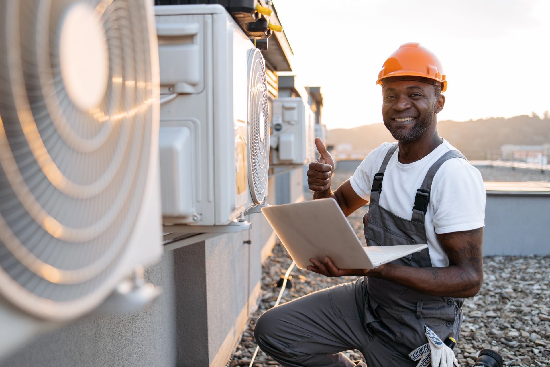 HVAC technician wearing mask and hard hat, working on AC units on a rooftop. HVAC technician wearing mask and hard hat, working on AC units on a rooftop.