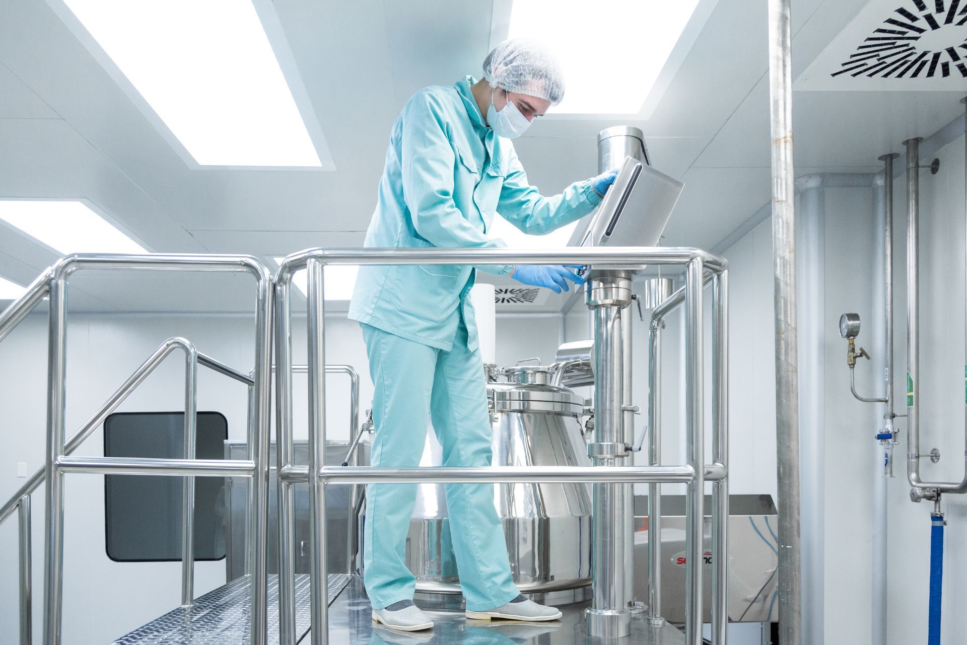 HVAC technician wearing mask and hard hat, working on AC units on a rooftop.