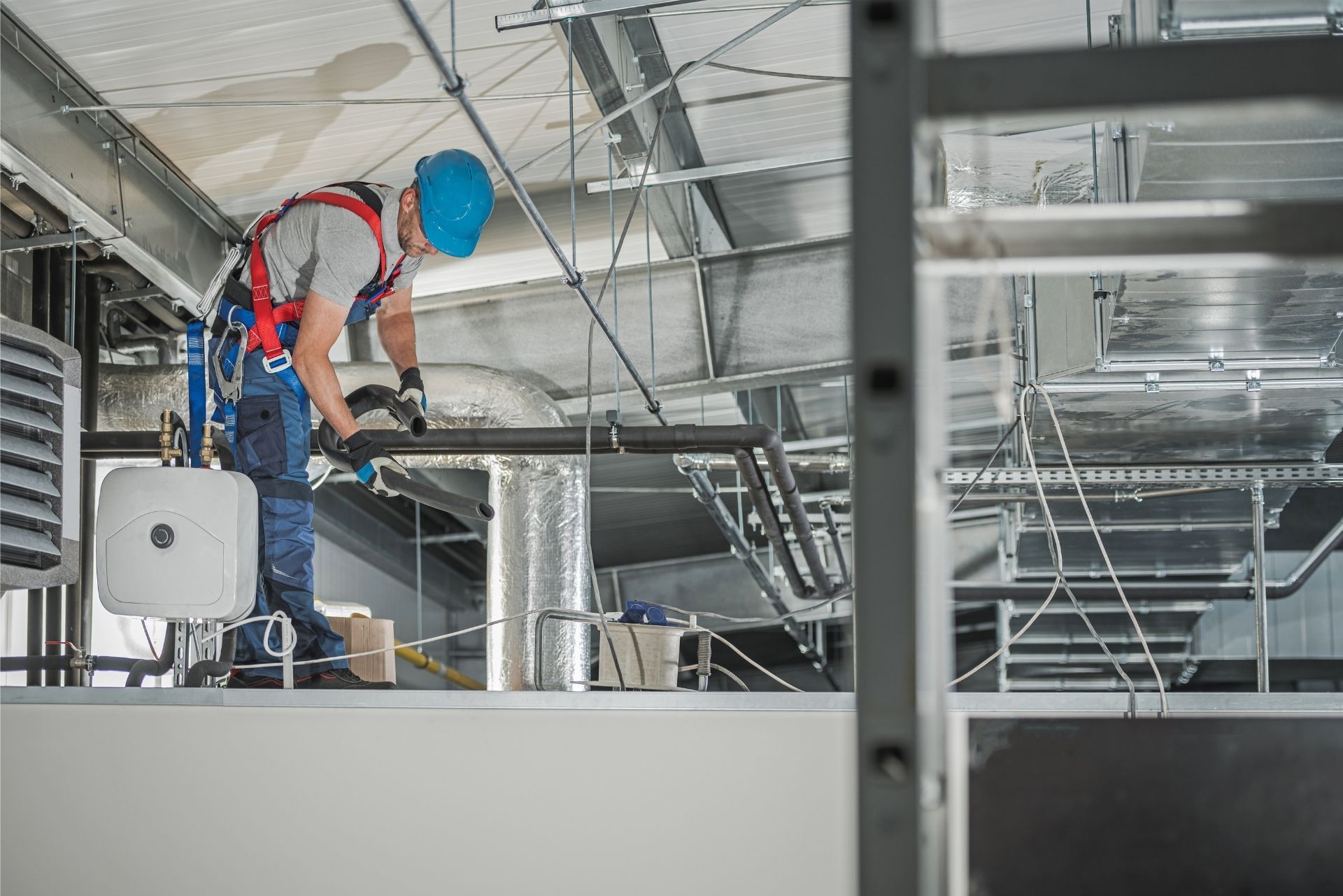HVAC technician wearing mask and hard hat, working on AC units on a rooftop. HVAC technician wearing mask and hard hat, working on AC units on a rooftop.