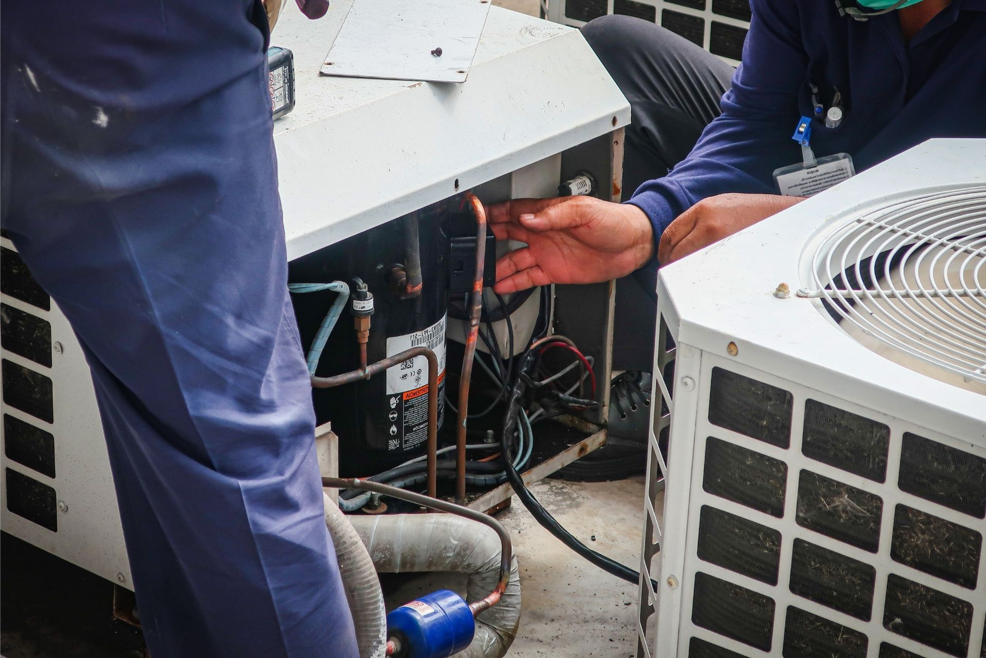 HVAC technician wearing mask and hard hat, working on AC units on a rooftop. HVAC technician wearing mask and hard hat, working on AC units on a rooftop.