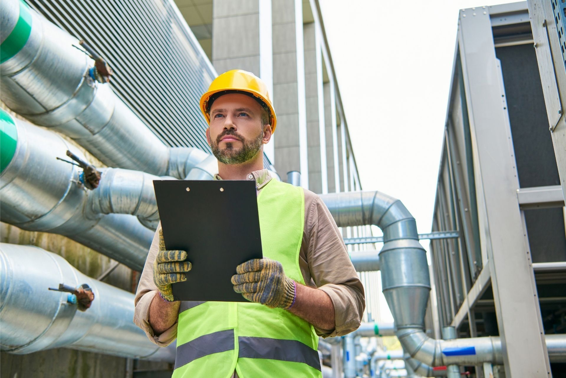 HVAC technician wearing mask and hard hat, working on AC units on a rooftop. HVAC technician wearing mask and hard hat, working on AC units on a rooftop.
