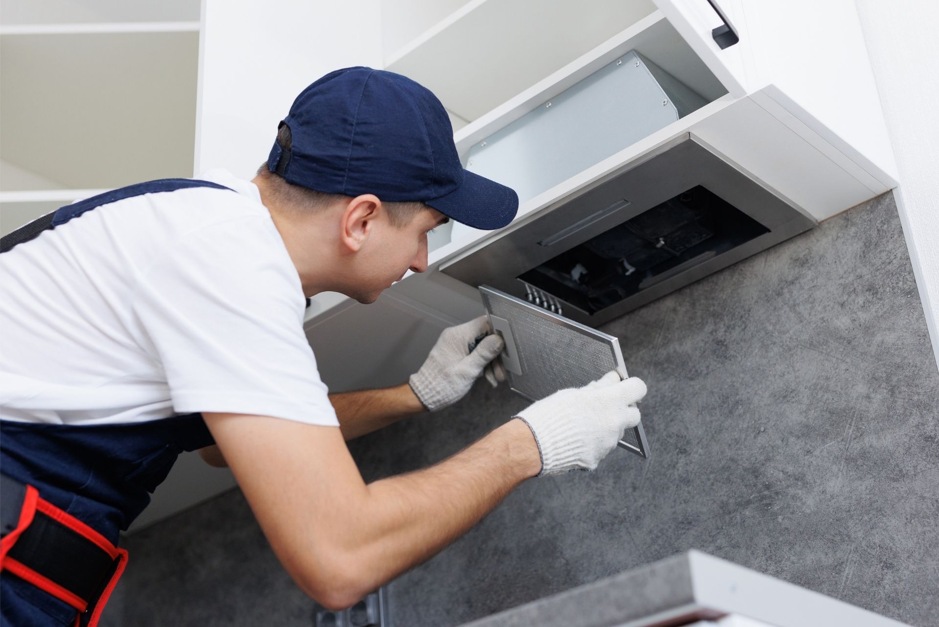 HVAC technician wearing mask and hard hat, working on AC units on a rooftop.