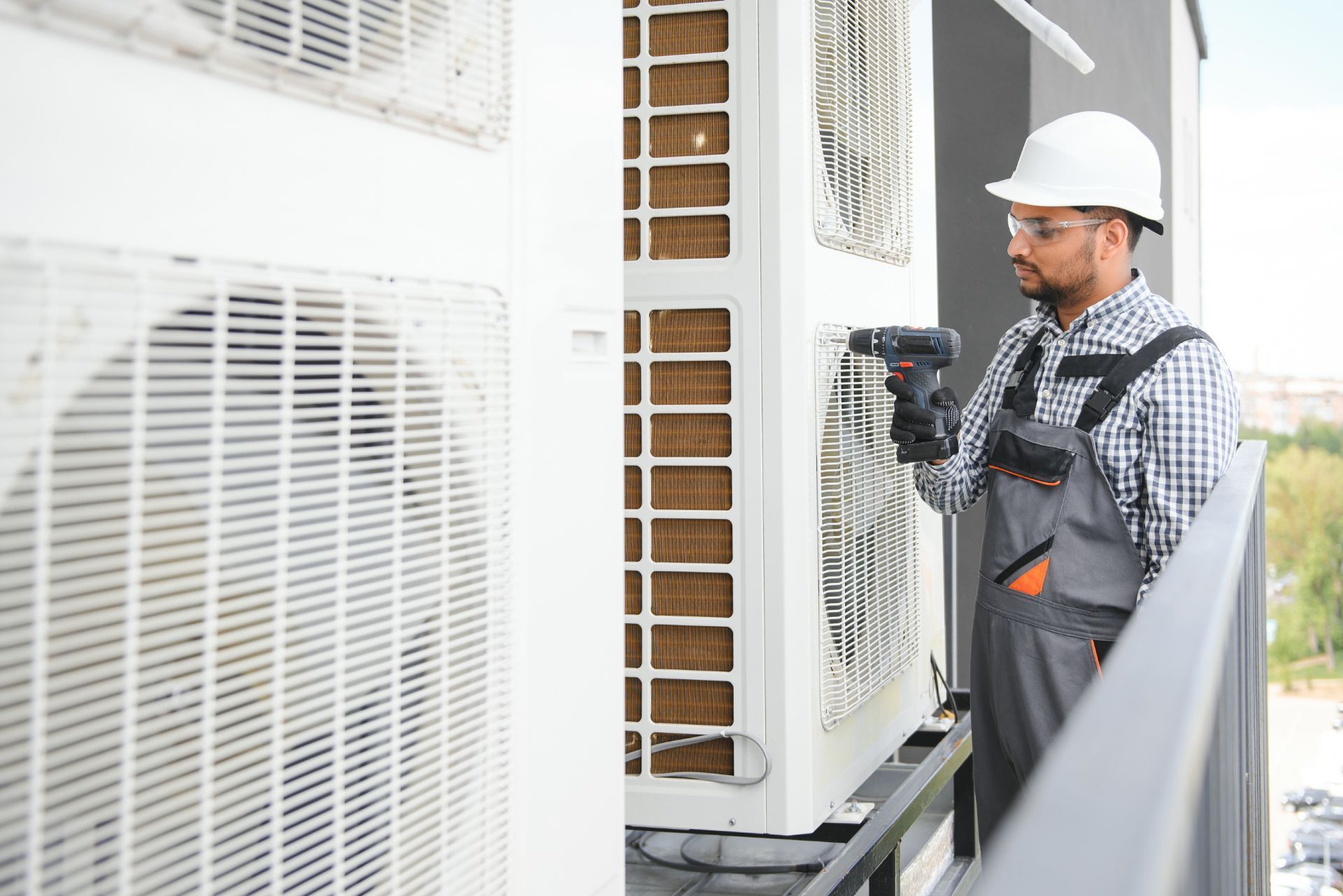 HVAC technician wearing mask and hard hat, working on AC units on a rooftop. HVAC technician wearing mask and hard hat, working on AC units on a rooftop.
