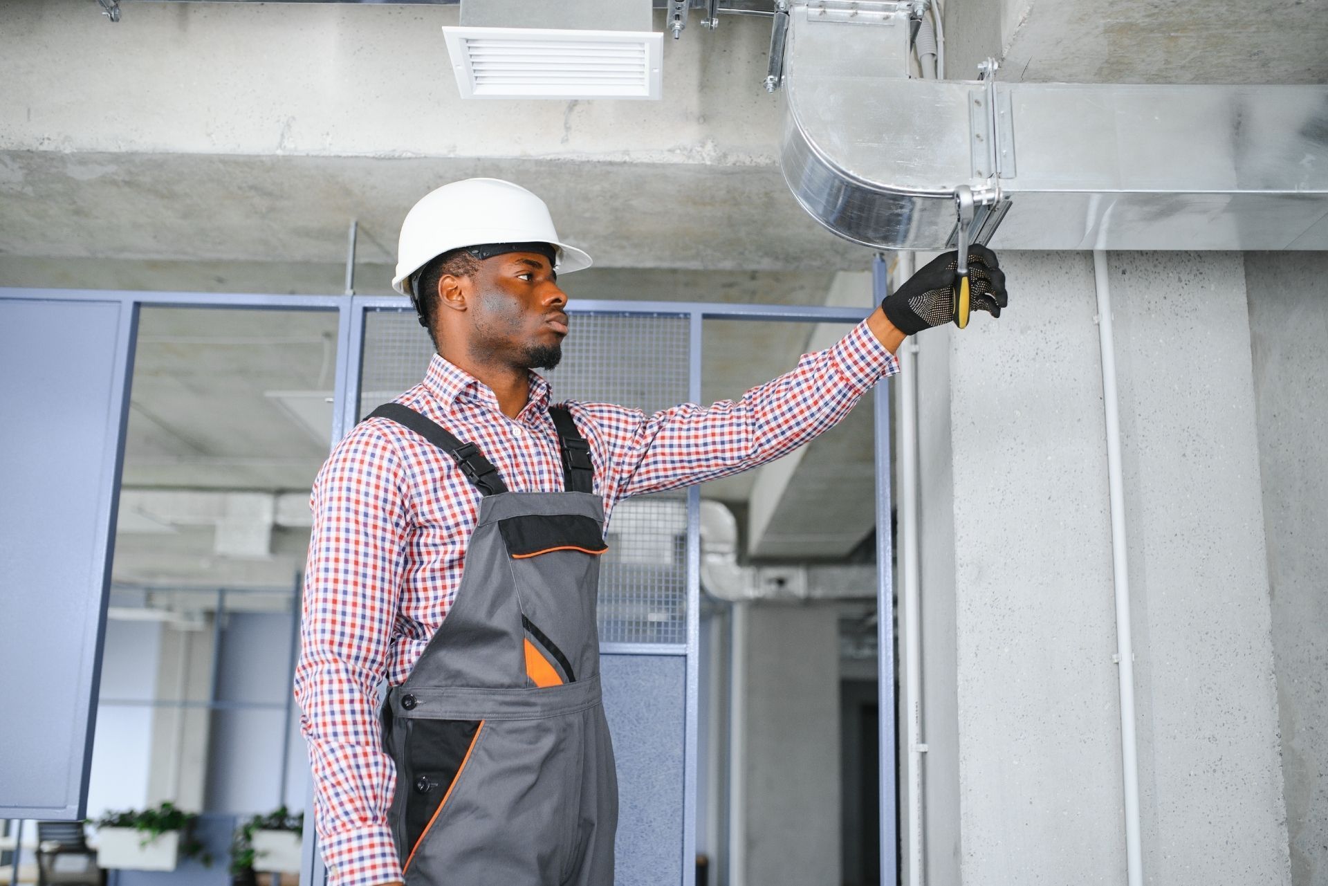 HVAC technician wearing mask and hard hat, working on AC units on a rooftop. HVAC technician wearing mask and hard hat, working on AC units on a rooftop.