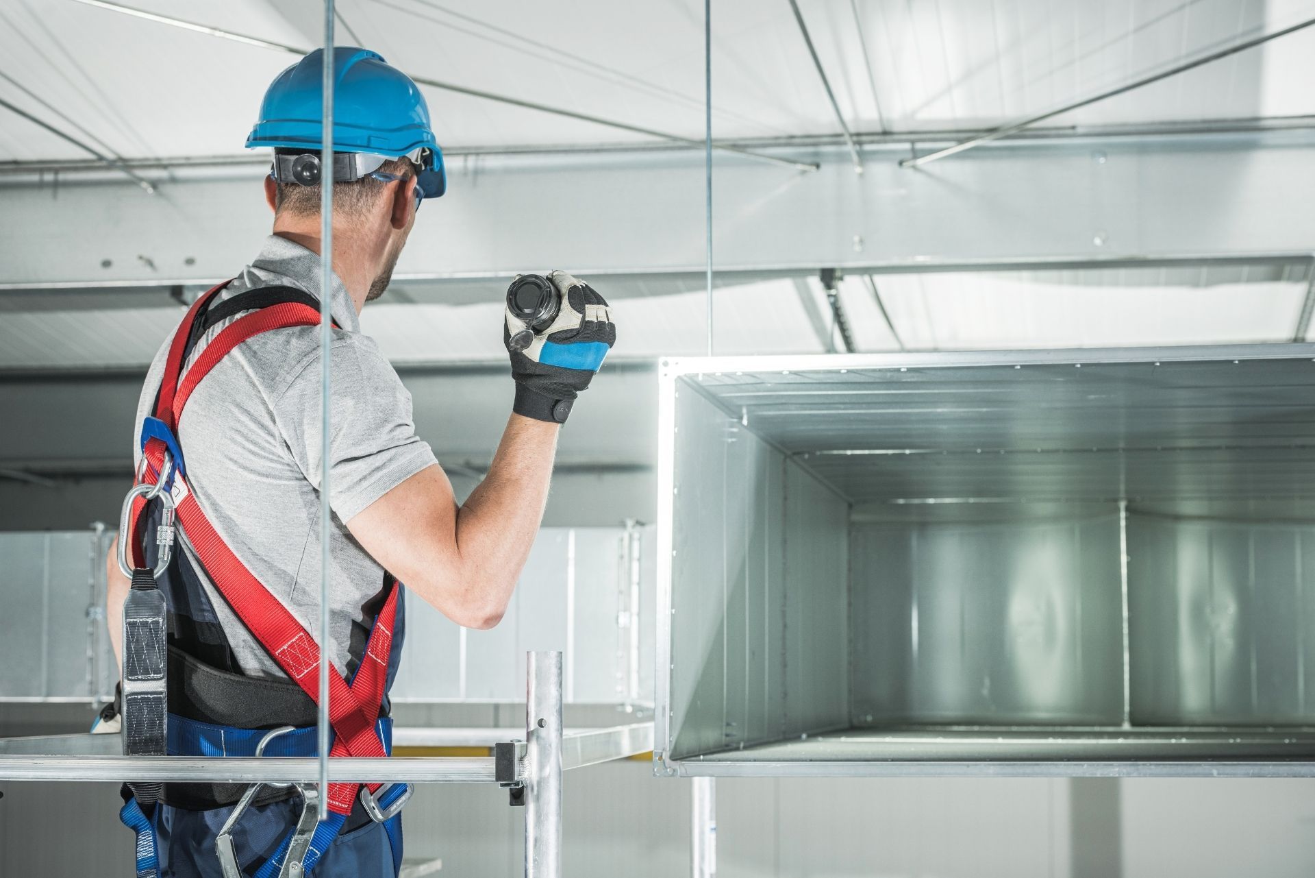 HVAC technician wearing mask and hard hat, working on AC units on a rooftop. HVAC technician wearing mask and hard hat, working on AC units on a rooftop.