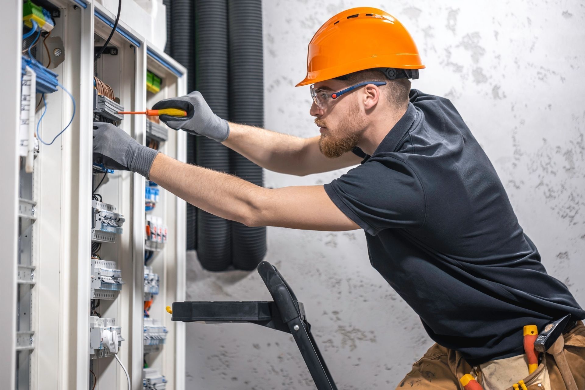 HVAC technician wearing mask and hard hat, working on AC units on a rooftop.