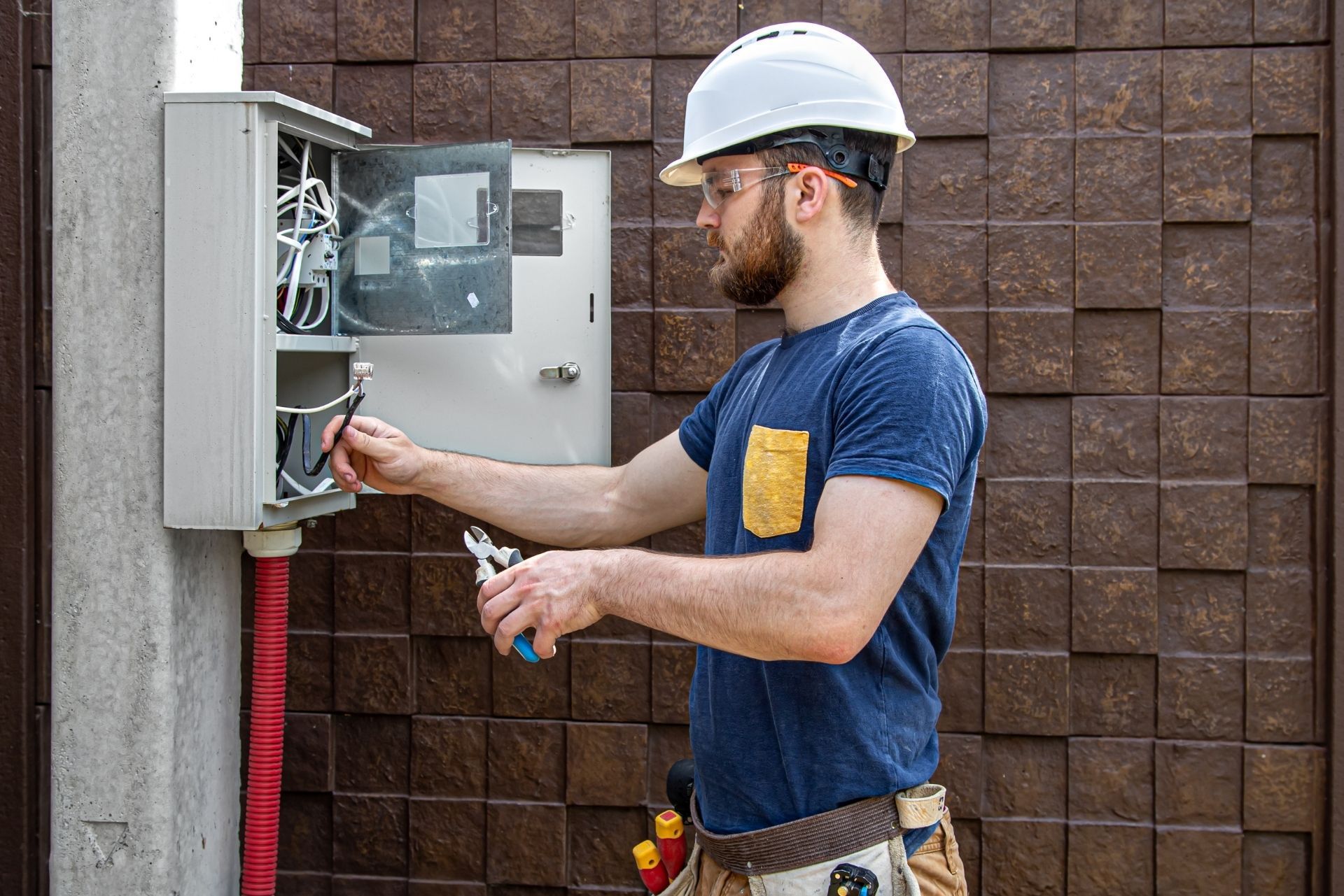 HVAC technician wearing mask and hard hat, working on AC units on a rooftop.