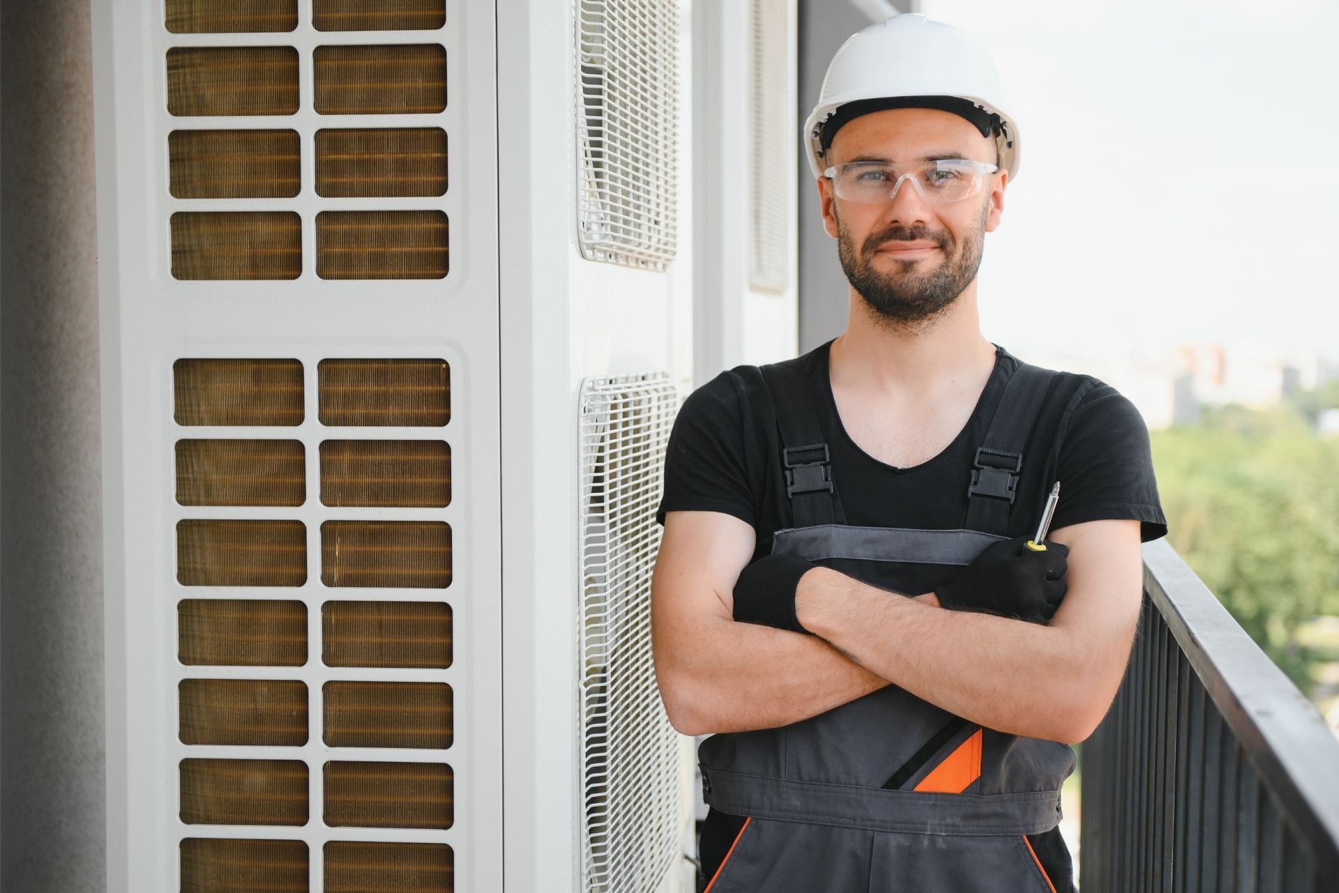 HVAC technician wearing mask and hard hat, working on AC units on a rooftop. HVAC technician wearing mask and hard hat, working on AC units on a rooftop.
