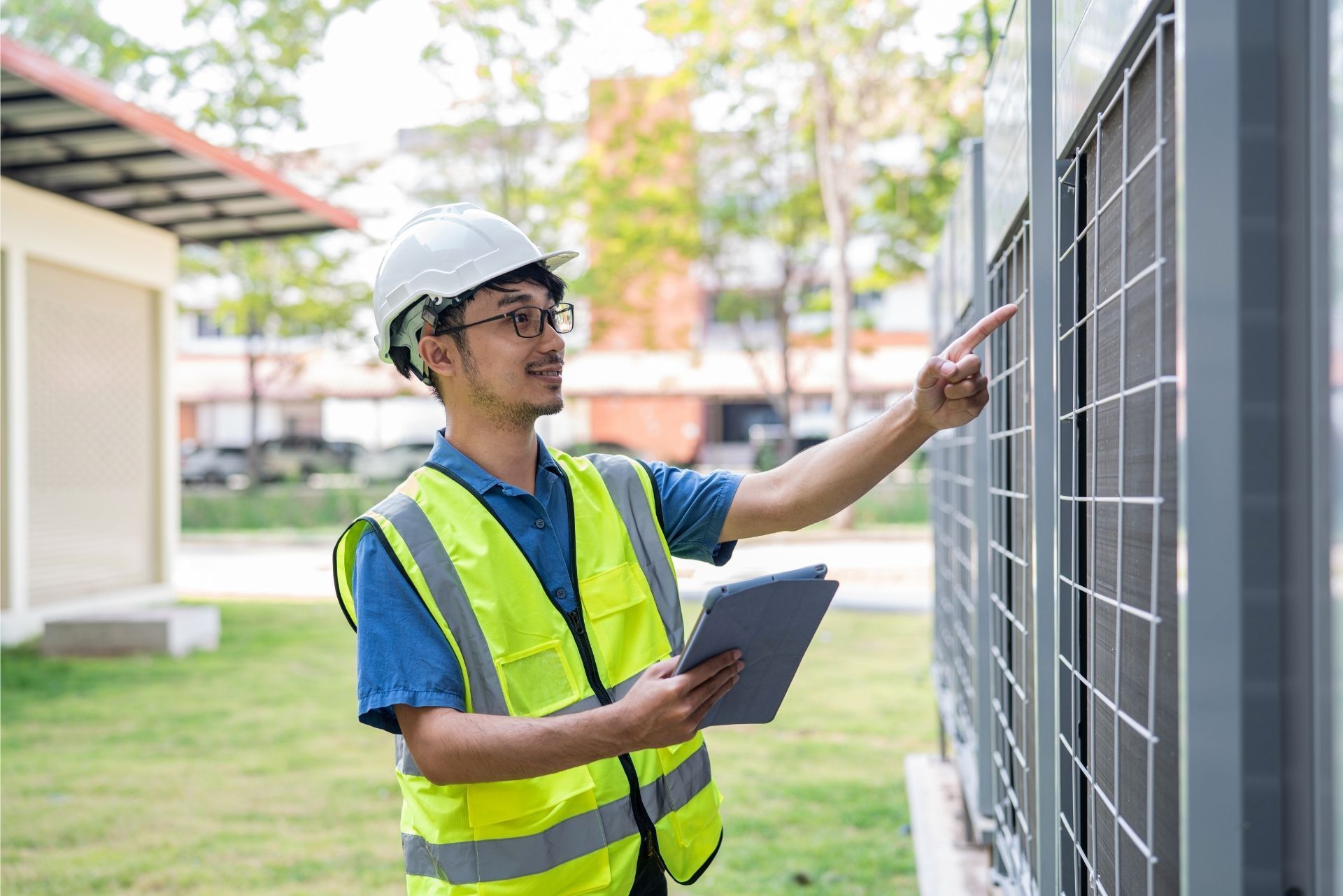 HVAC technician wearing mask and hard hat, working on AC units on a rooftop.
