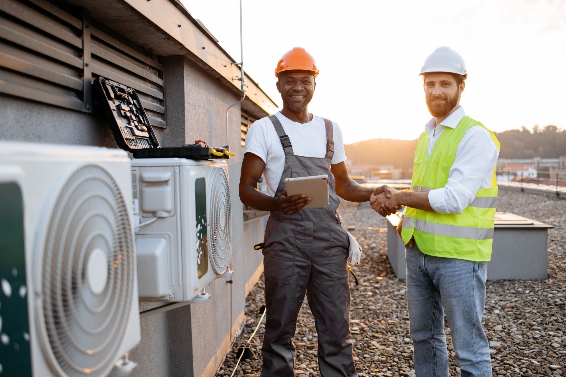 HVAC technician wearing mask and hard hat, working on AC units on a rooftop. HVAC technician wearing mask and hard hat, working on AC units on a rooftop.