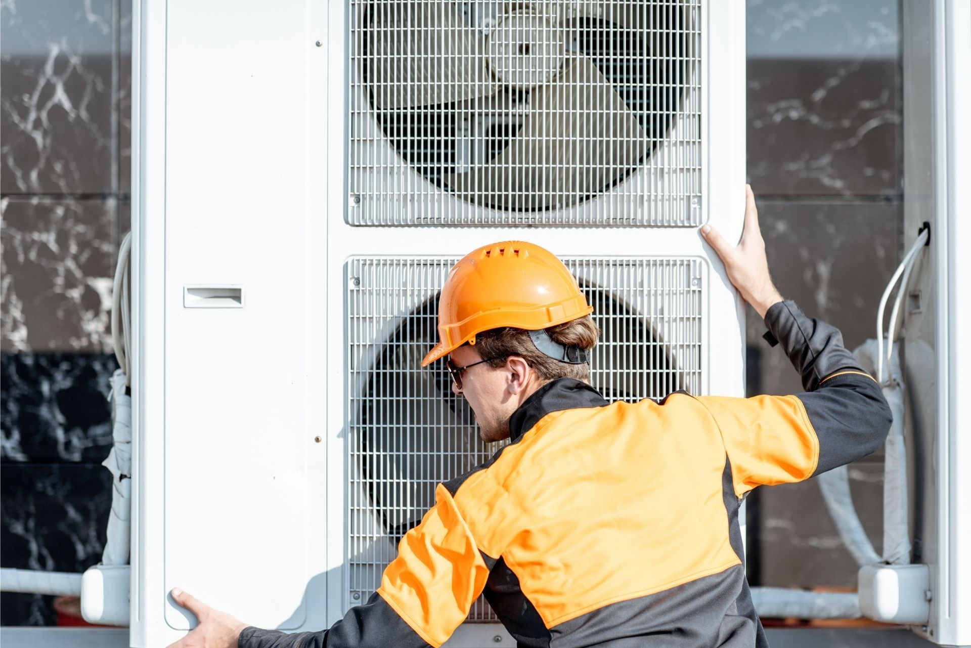HVAC technician wearing mask and hard hat, working on AC units on a rooftop. HVAC technician wearing mask and hard hat, working on AC units on a rooftop.
