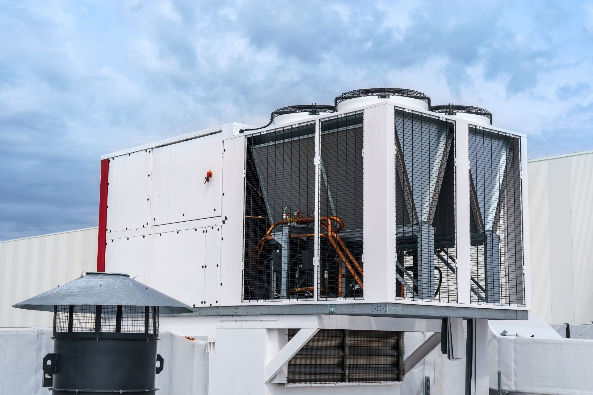HVAC technician wearing mask and hard hat, working on AC units on a rooftop.