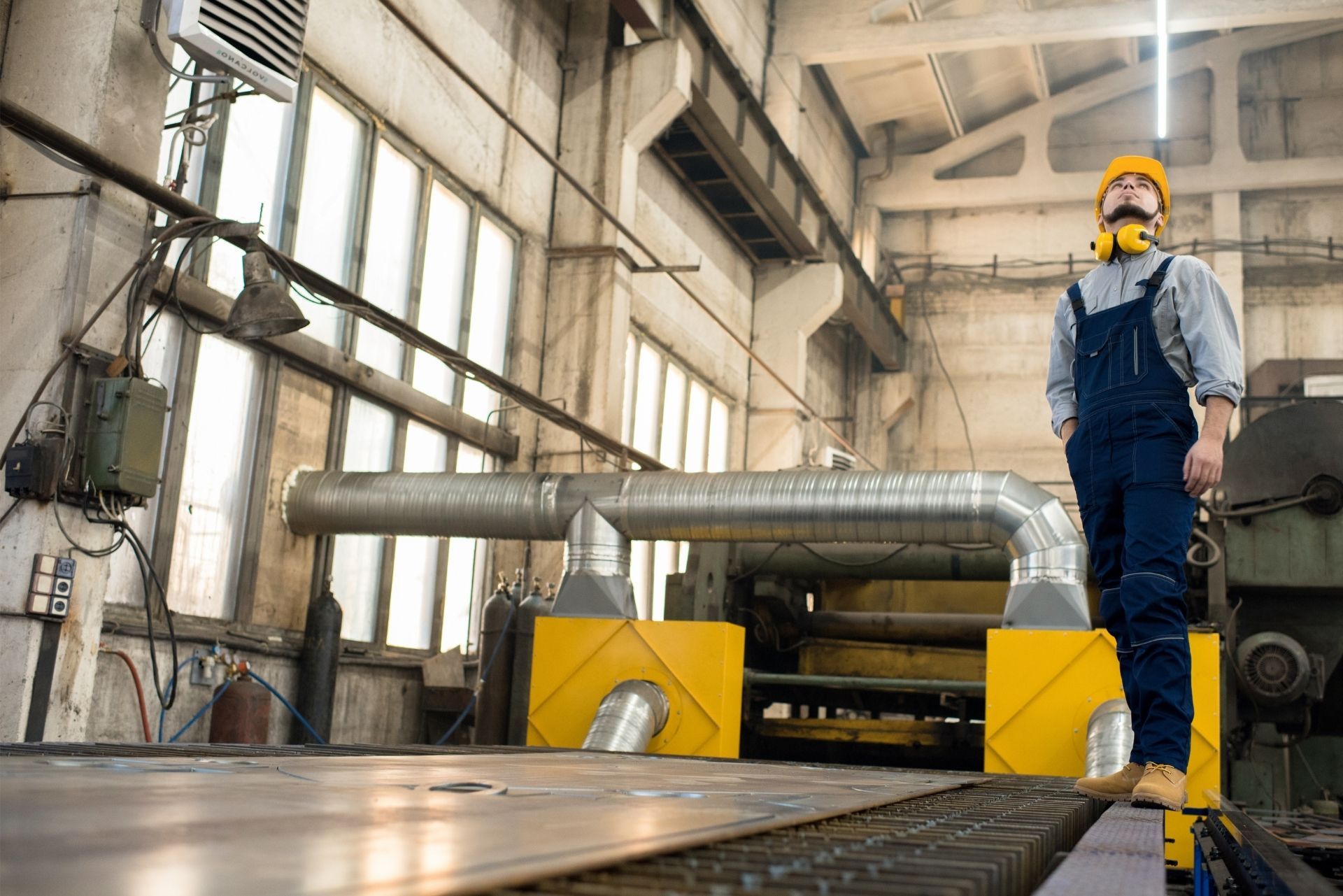 HVAC technician wearing mask and hard hat, working on AC units on a rooftop. HVAC technician wearing mask and hard hat, working on AC units on a rooftop.