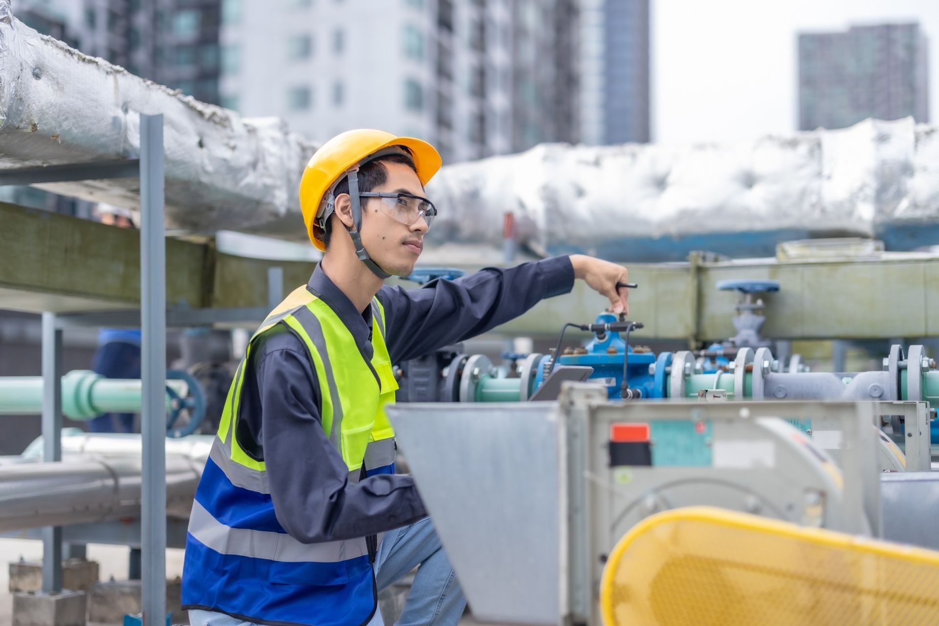 HVAC technician wearing mask and hard hat, working on AC units on a rooftop. HVAC technician wearing mask and hard hat, working on AC units on a rooftop.