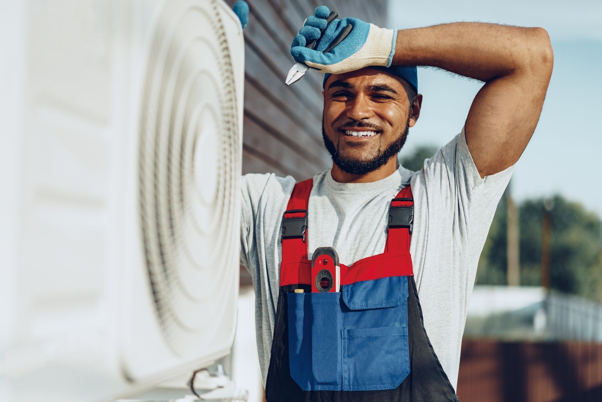 HVAC technician wearing mask and hard hat, working on AC units on a rooftop. HVAC technician wearing mask and hard hat, working on AC units on a rooftop.