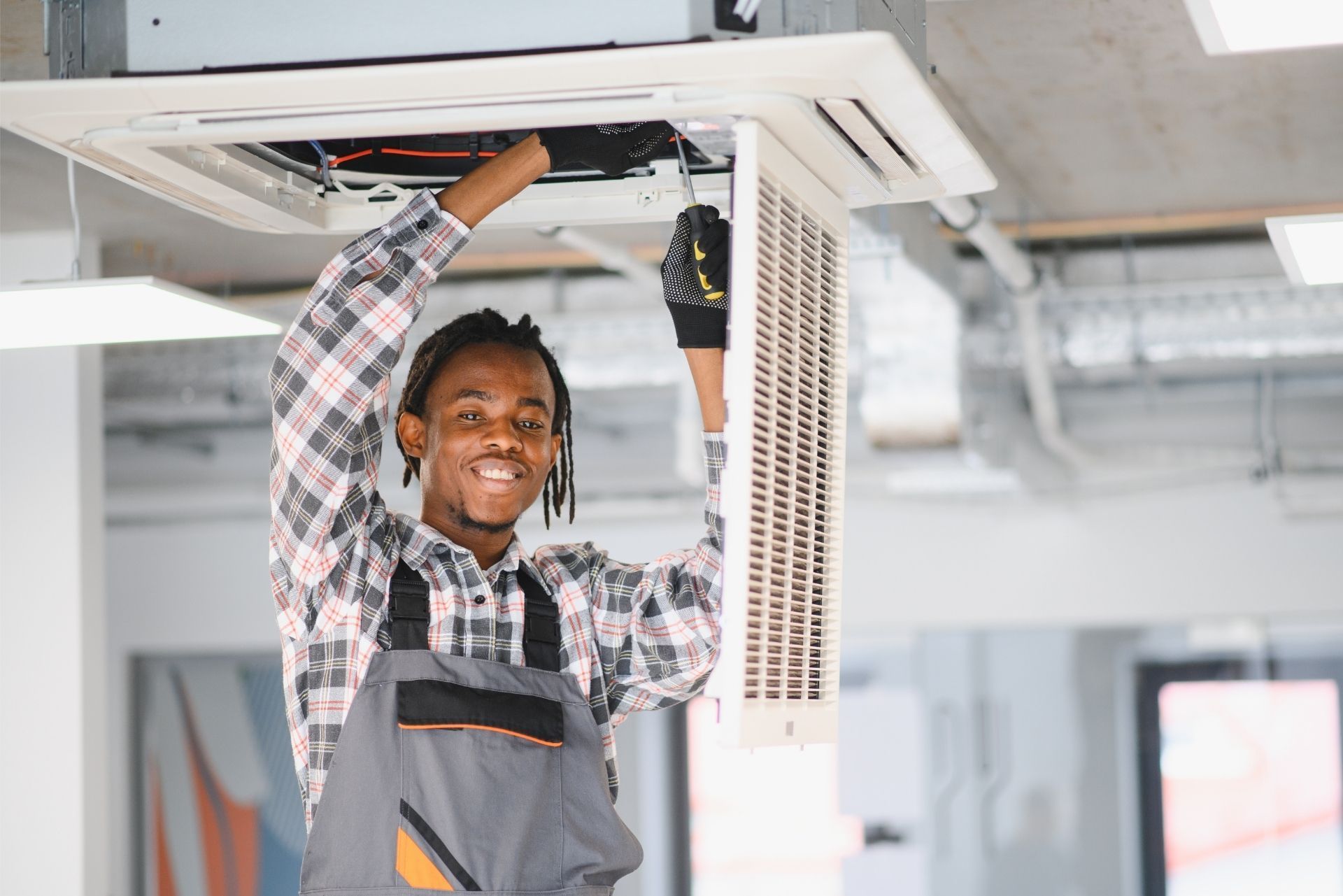 HVAC technician wearing mask and hard hat, working on AC units on a rooftop. HVAC technician wearing mask and hard hat, working on AC units on a rooftop.
