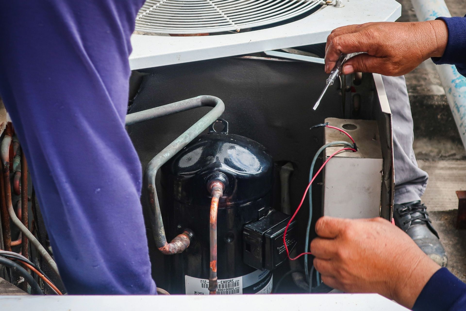 HVAC technician wearing mask and hard hat, working on AC units on a rooftop. HVAC technician wearing mask and hard hat, working on AC units on a rooftop.