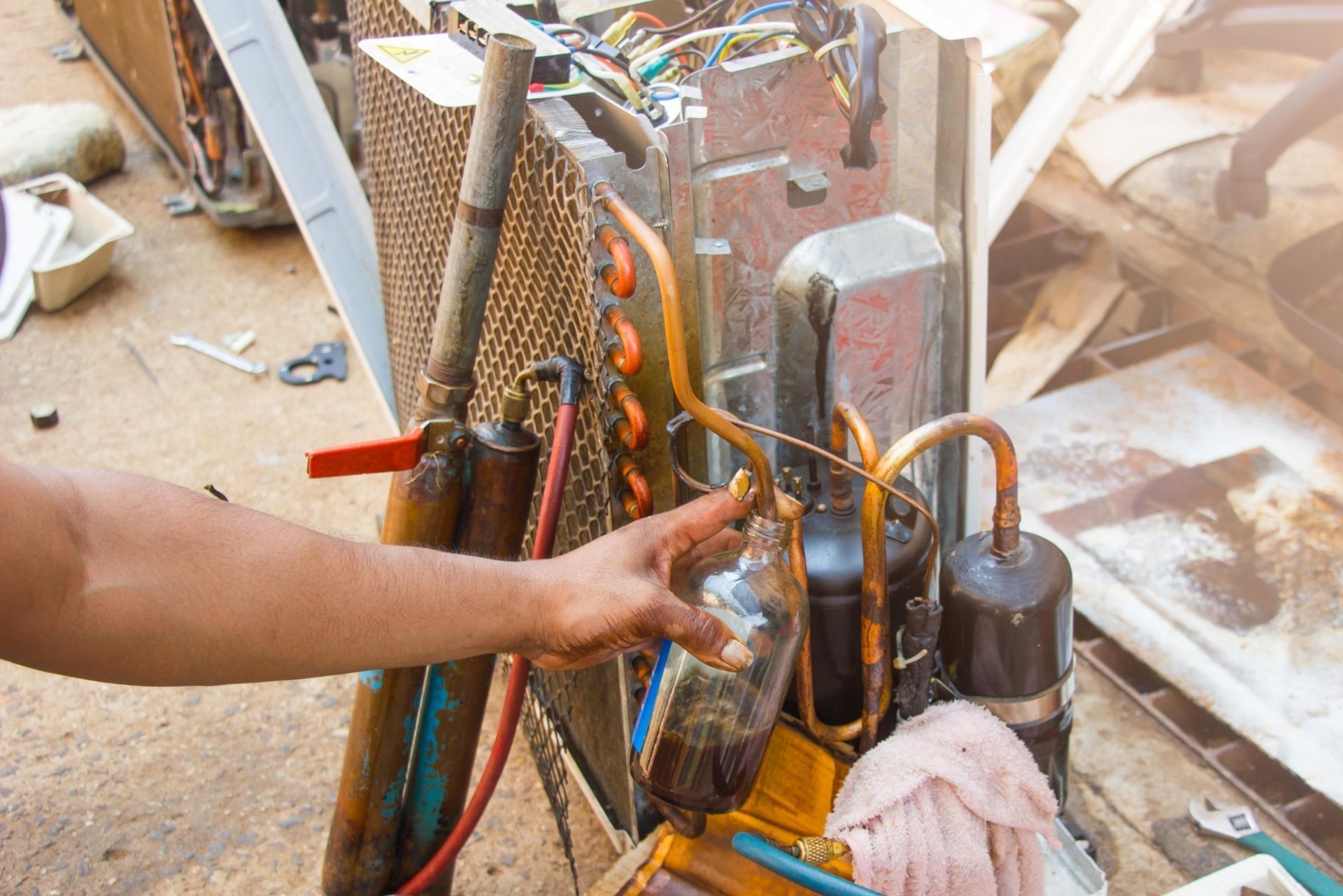 HVAC technician wearing mask and hard hat, working on AC units on a rooftop.