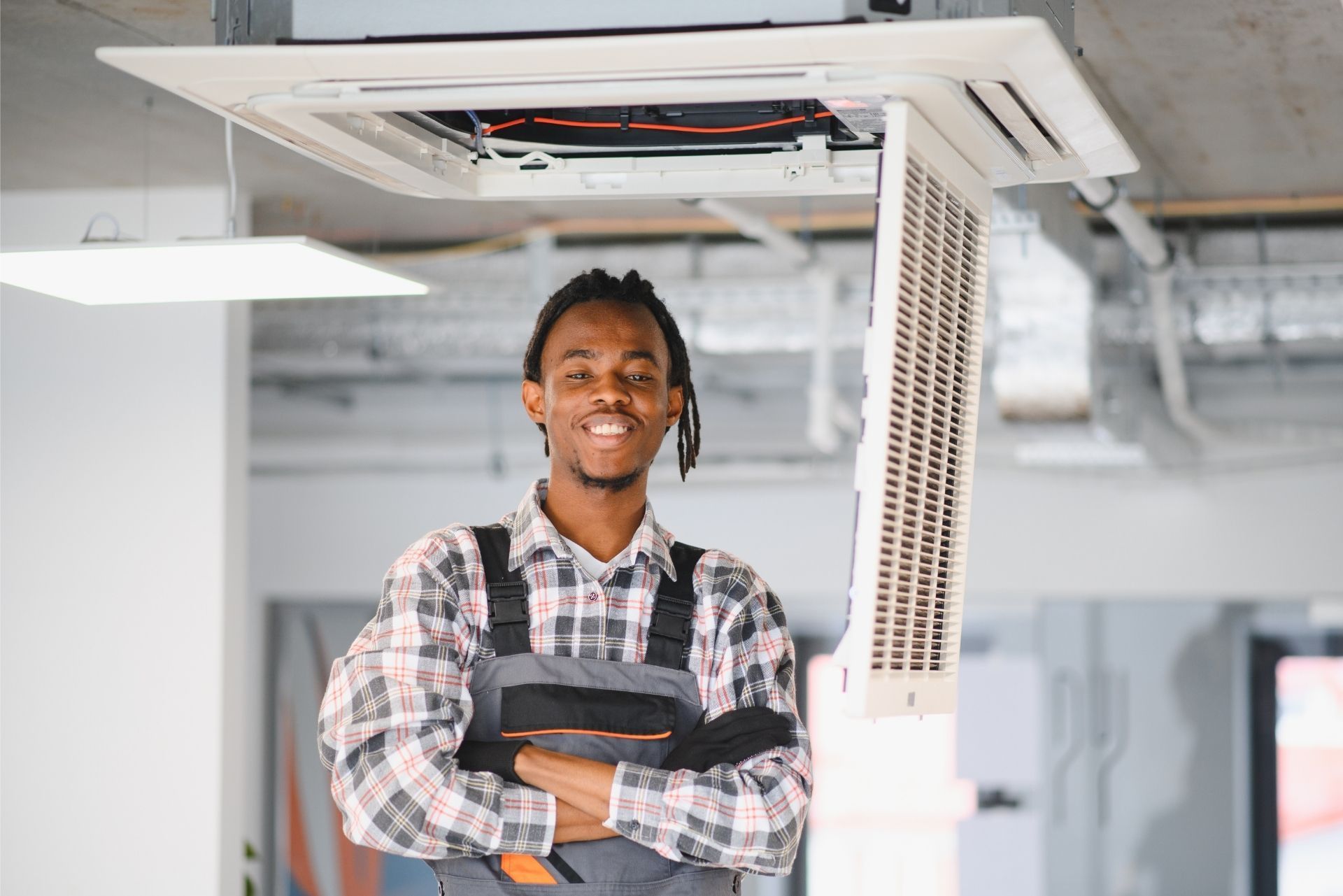 HVAC technician wearing mask and hard hat, working on AC units on a rooftop. HVAC technician wearing mask and hard hat, working on AC units on a rooftop.