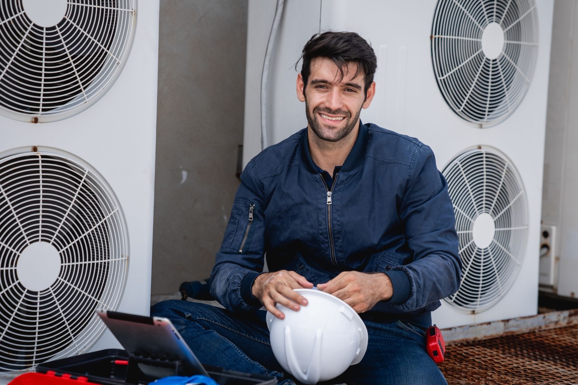HVAC technician wearing mask and hard hat, working on AC units on a rooftop. HVAC technician wearing mask and hard hat, working on AC units on a rooftop.