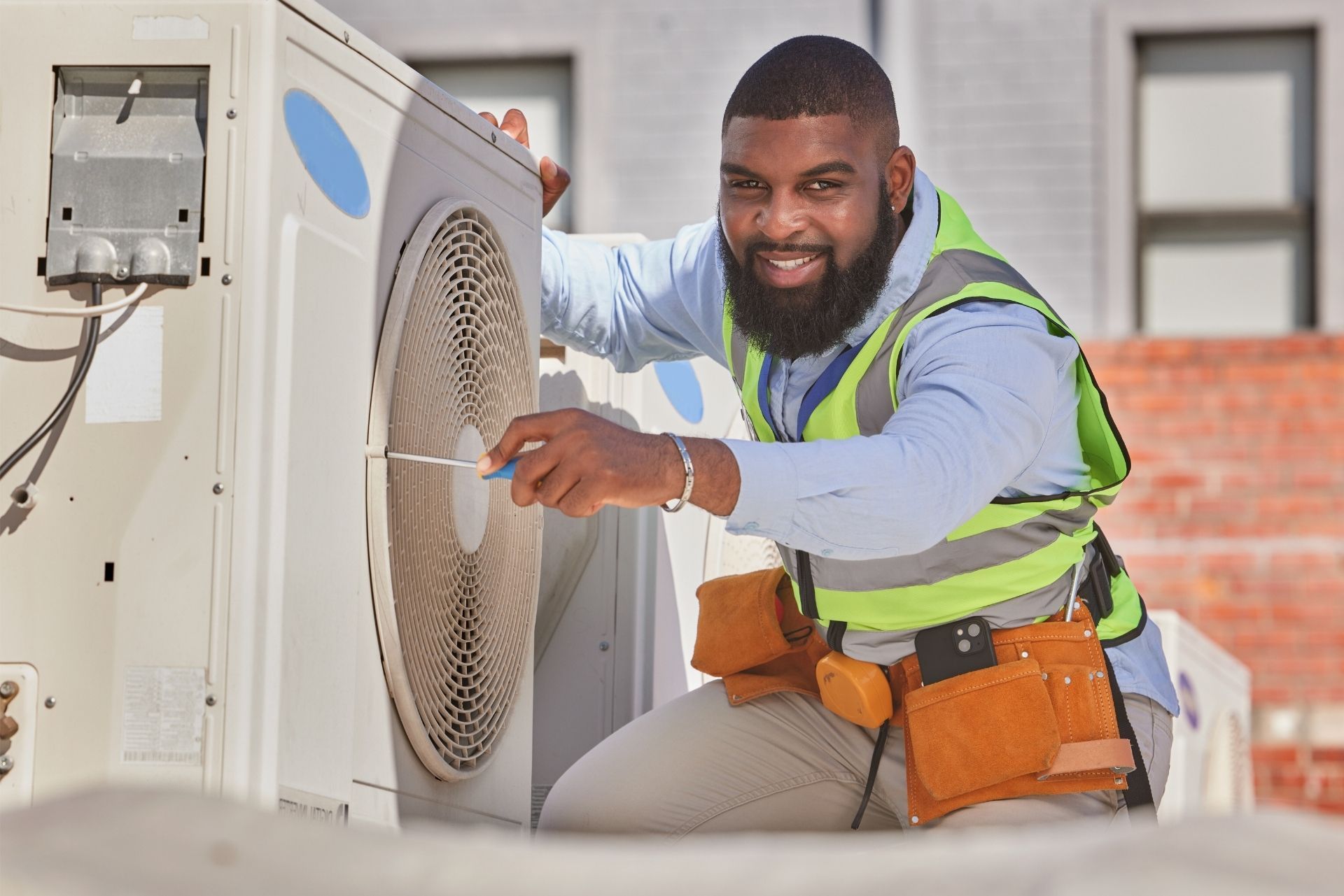 HVAC technician wearing mask and hard hat, working on AC units on a rooftop. HVAC technician wearing mask and hard hat, working on AC units on a rooftop.