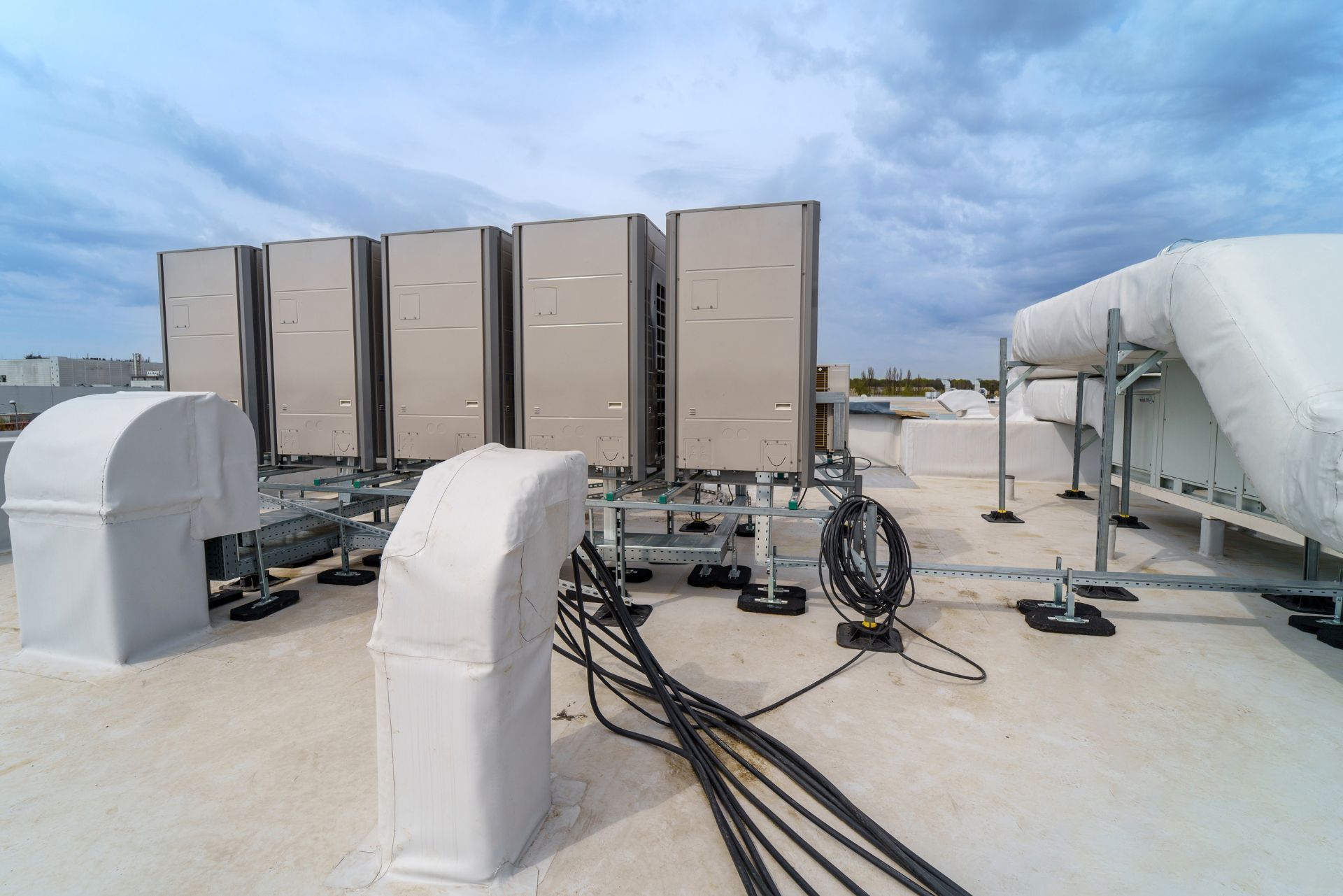 HVAC technician wearing mask and hard hat, working on AC units on a rooftop. HVAC technician wearing mask and hard hat, working on AC units on a rooftop.