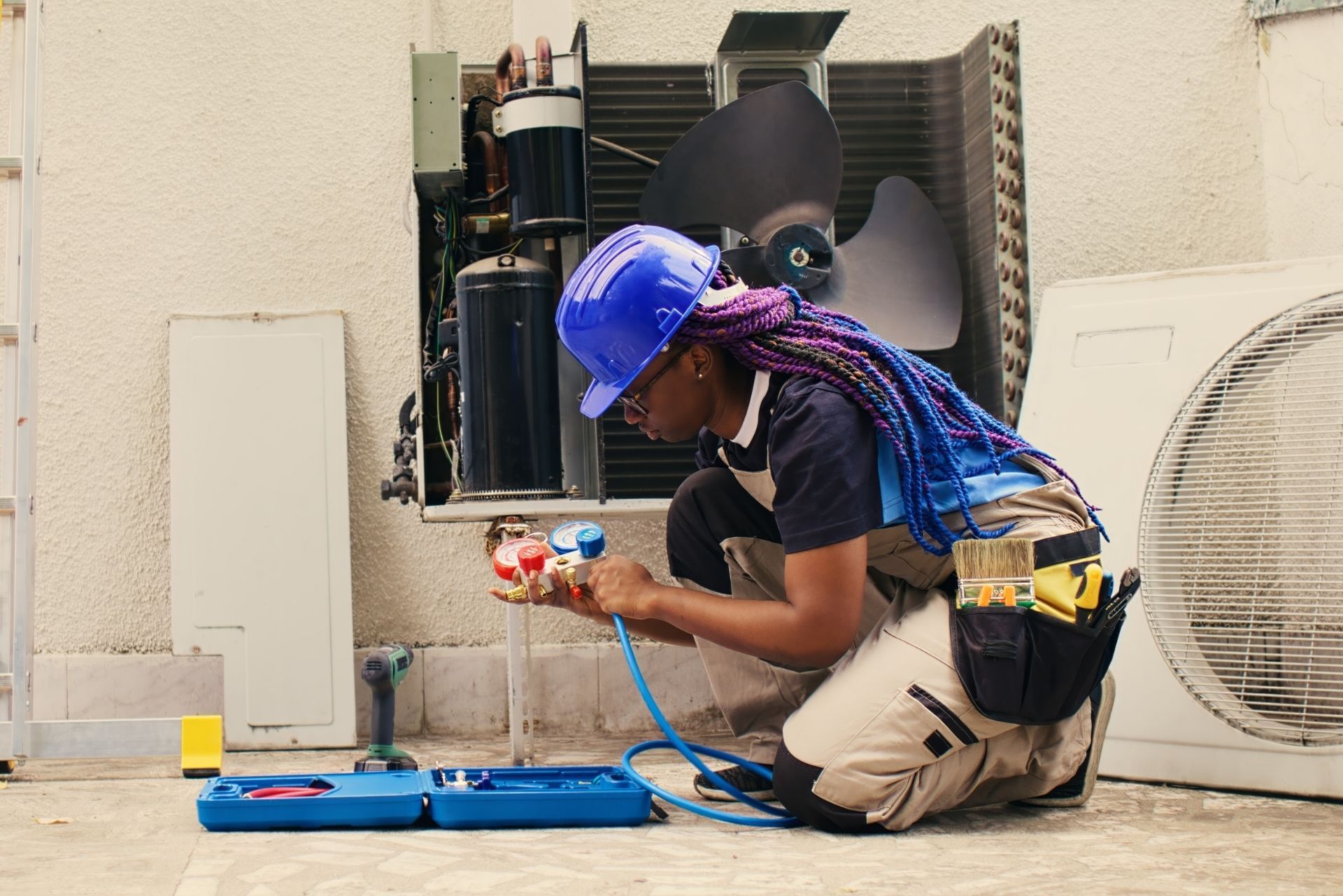 HVAC technician wearing mask and hard hat, working on AC units on a rooftop. HVAC technician wearing mask and hard hat, working on AC units on a rooftop.