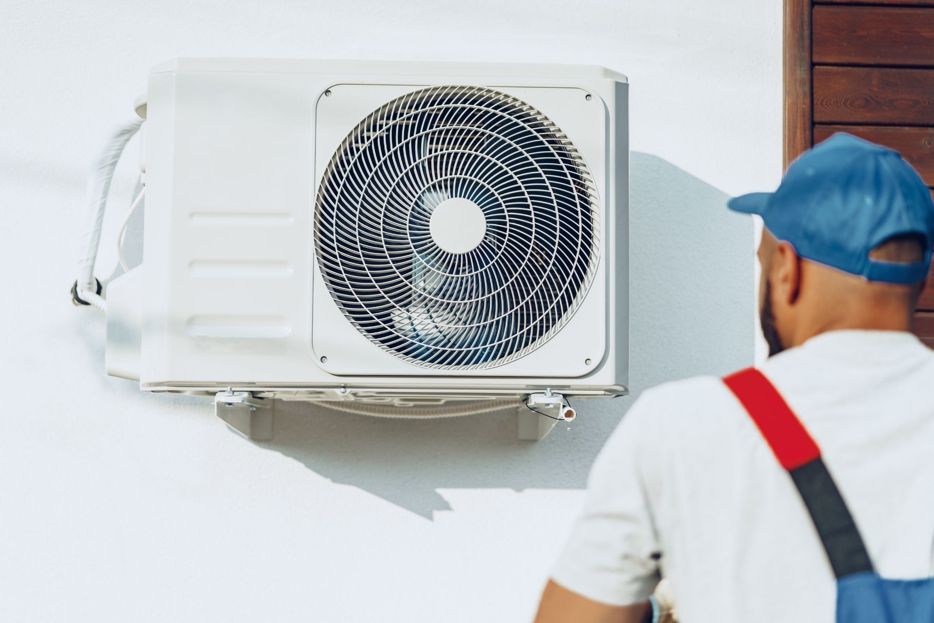HVAC technician wearing mask and hard hat, working on AC units on a rooftop. HVAC technician wearing mask and hard hat, working on AC units on a rooftop.