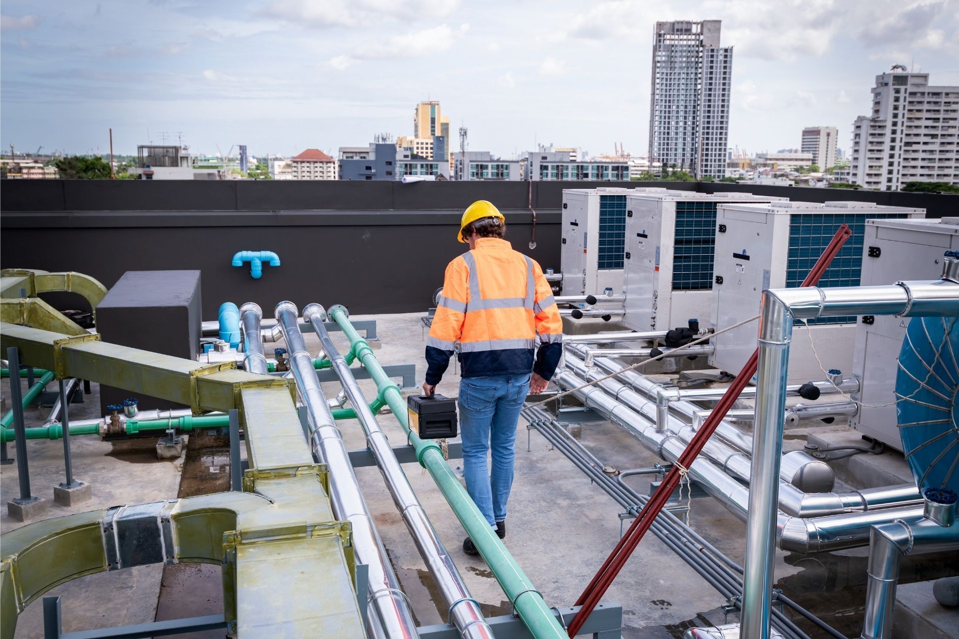 HVAC technician wearing mask and hard hat, working on AC units on a rooftop. HVAC technician wearing mask and hard hat, working on AC units on a rooftop.