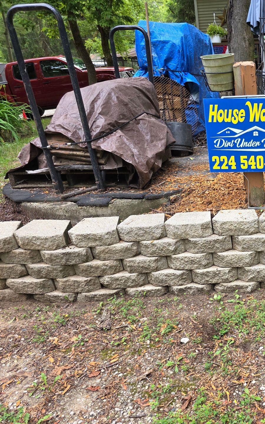 A yard with a retaining wall, cart, and a sign for