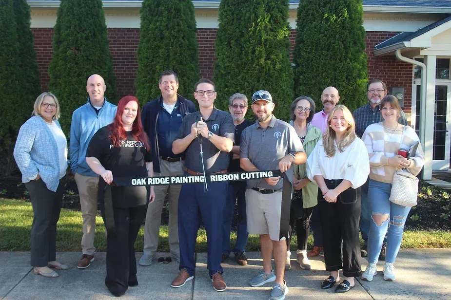 A group of people are standing in front of a building cutting a ribbon.